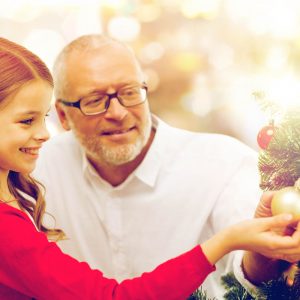 child and adult decorate a tree during the holiday season