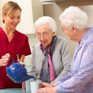 Nurse pours tea for two elderly women