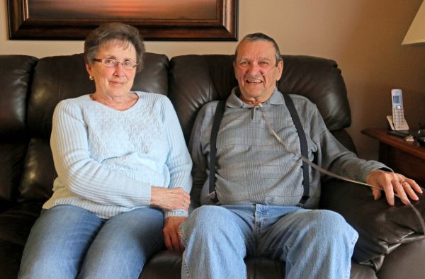 Karen and Bill Kelly sit side by side on their living room couch.