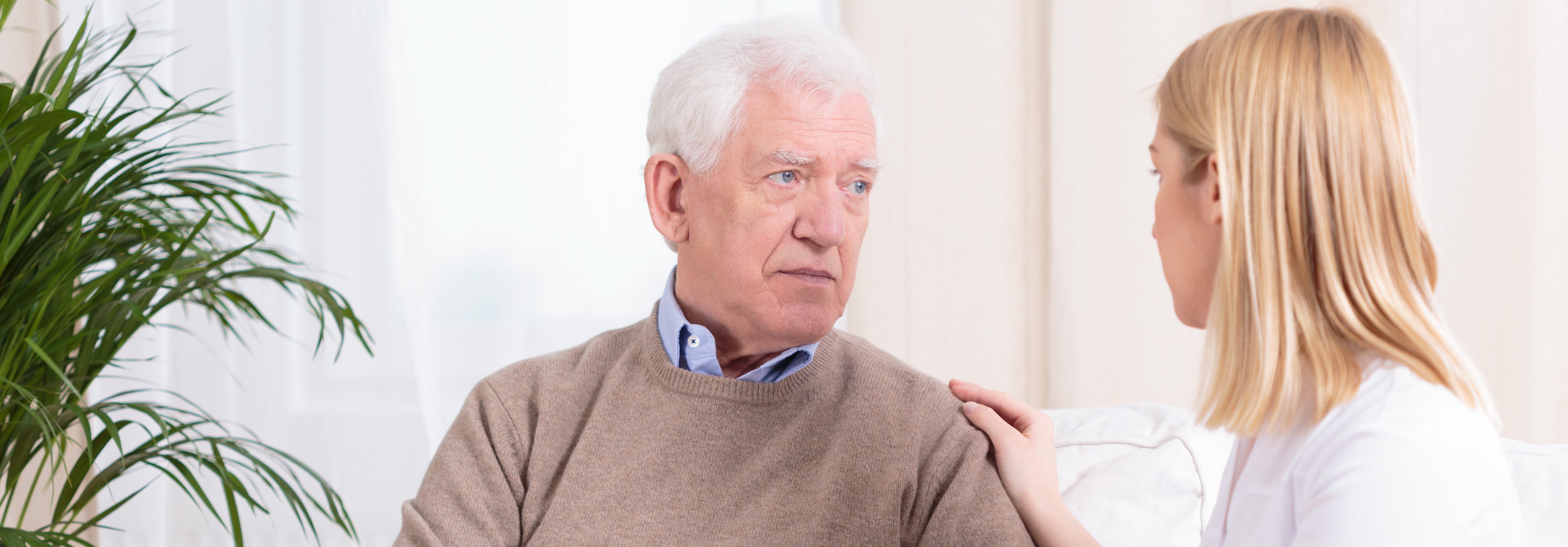 Young careful nurse holding aged man's arm