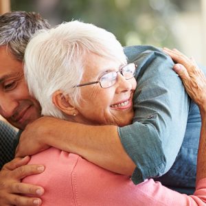 Middle aged man hugging elderly woman