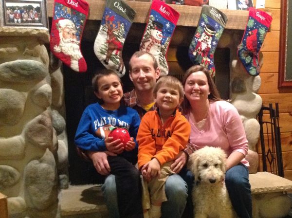 Neimeier family sitting in front of fireplace_christmas stockings above head