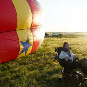 Mary Sluke sitting near a hot air balloon