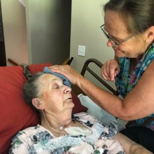 grandma's forehead gently caressed with a washcloth by her daughter