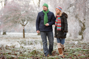 couple walking outside in frost covered grass and trees