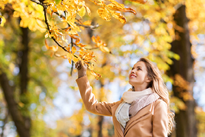 woman reaching for a branch with yellow leaves