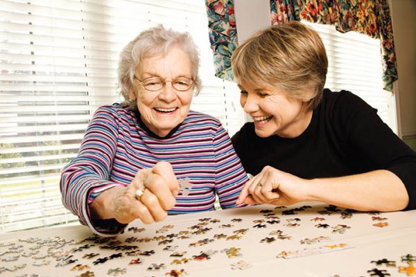 Woman playing puzzle with elderly woman