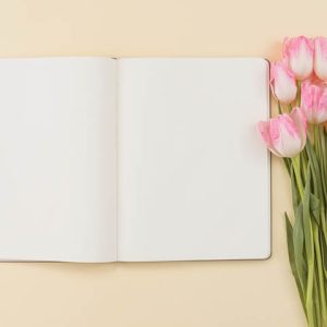 notebook with tulip flowers laying beside it