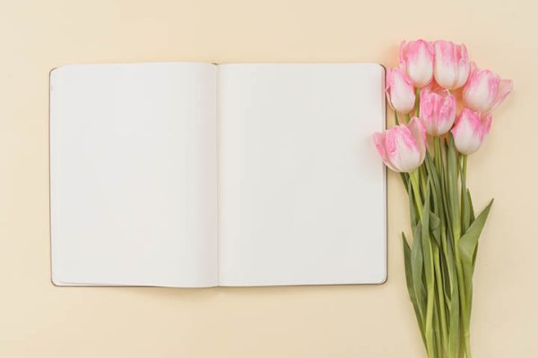 notebook with tulip flowers laying beside it