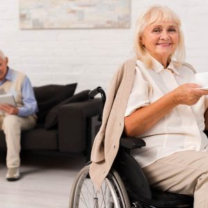 elderly woman sitting in wheelchair holding a tea cup and saucer
