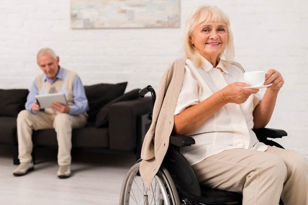 elderly woman sitting in wheelchair holding a tea cup and saucer